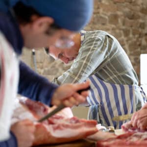 Stagiaires en train de découper de la viande de porc aux gaties